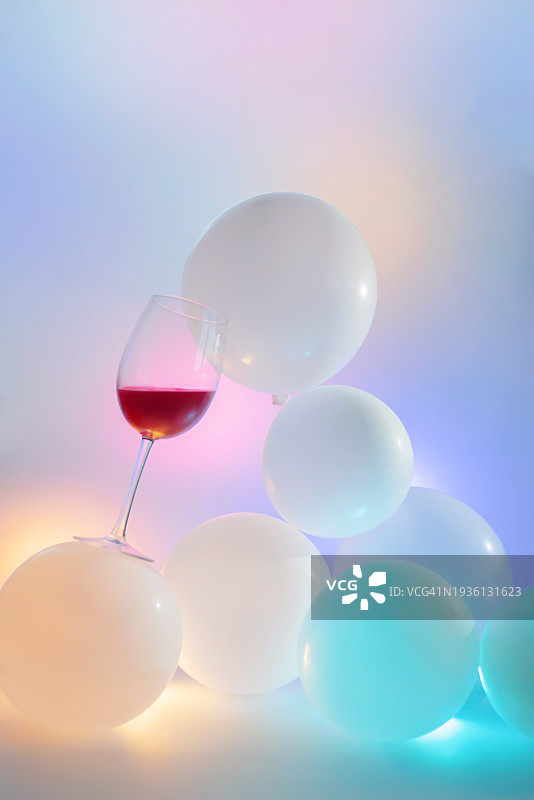 梦幻粉彩色调中白色气球上平衡的酒杯，不稳定的构图图片素材