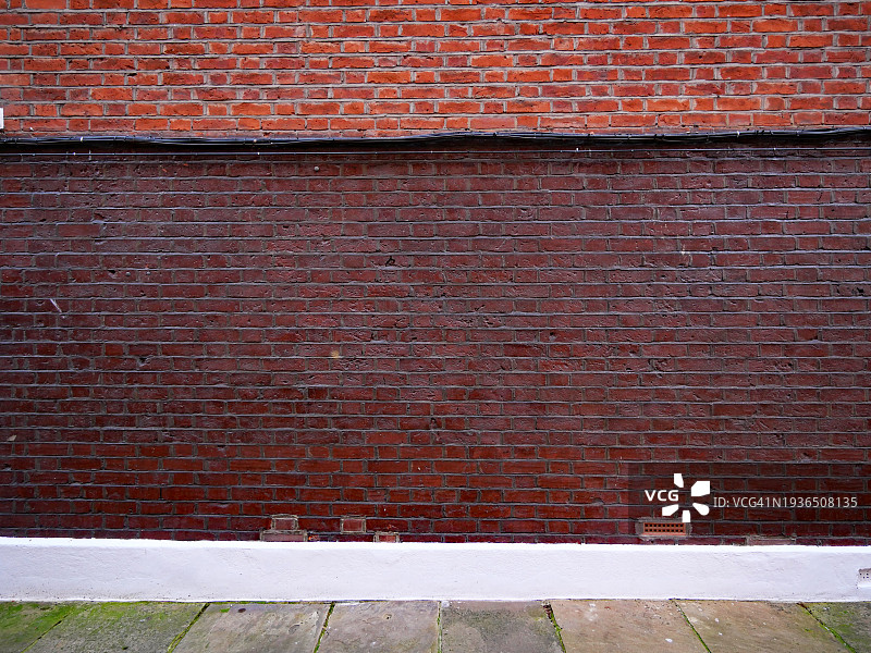 英国伦敦空旷干净的棕红色砖墙，带有电缆。风化的石头人行道。日光。自然色。图片素材