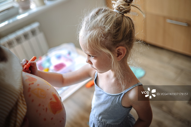 温馨阳光的家中，孕妇肚子上儿童的特写艺术作品图片素材