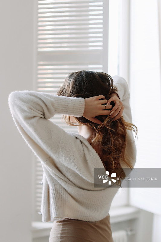 快乐的卷发女子在家中望着窗外，心理健康图片素材