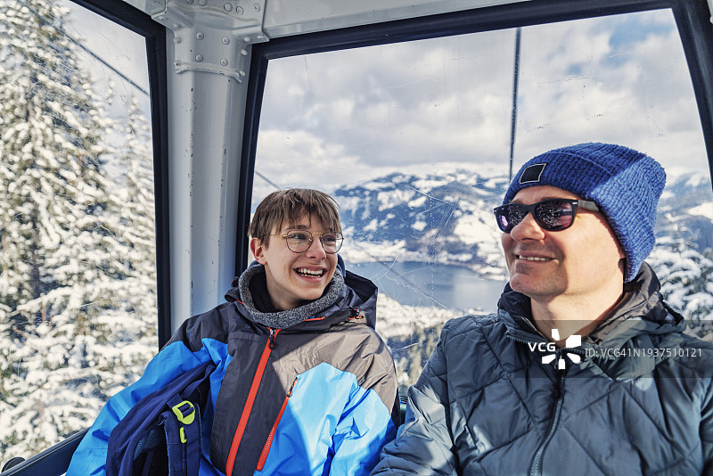 父与十几岁的儿子在冬日乘坐缆车图片素材