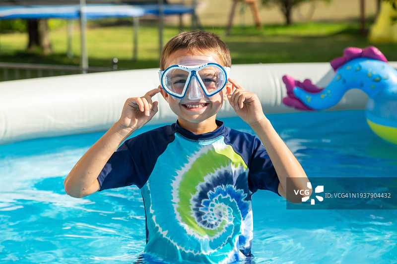 男孩戴着护目镜在后院泳池里图片素材