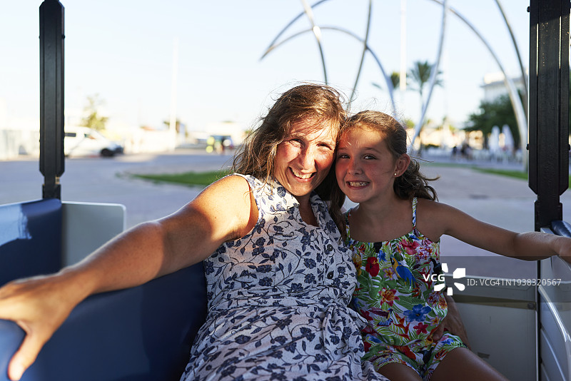 穿着连衣裙的游客和坐在观光车里的女儿的肖像图片素材