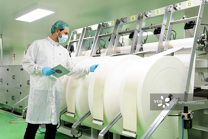 实验室技术员在传送带自动化机器上检查制造材料，口罩制造行业图片素材