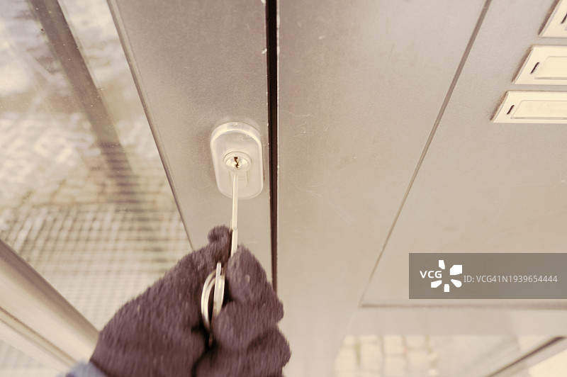 冬天，一人戴着黑色手套试图打开门口的门图片素材