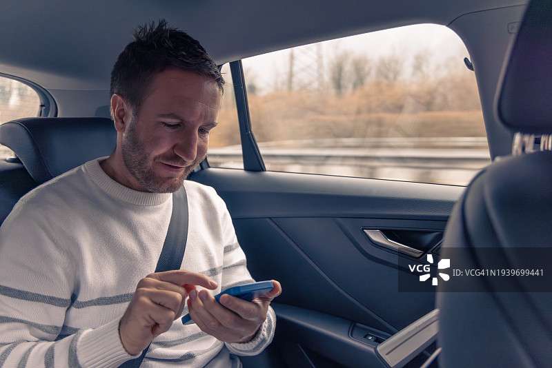 坐在出租车后座的白人商人使用智能手机图片素材