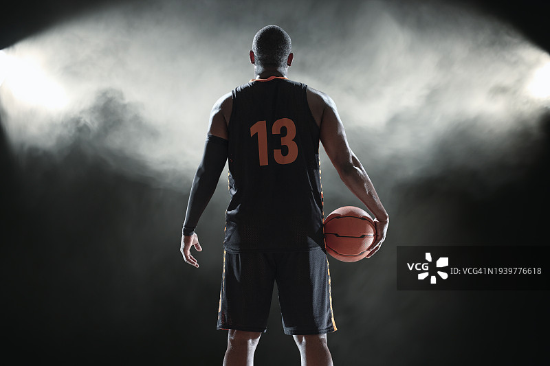 站在烟雾弥漫的黑暗背景下的黑人篮球运动员图片素材
