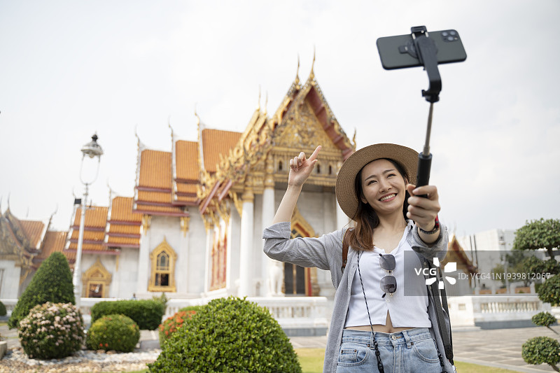 年轻女游客手持手机云台录制视频图片素材