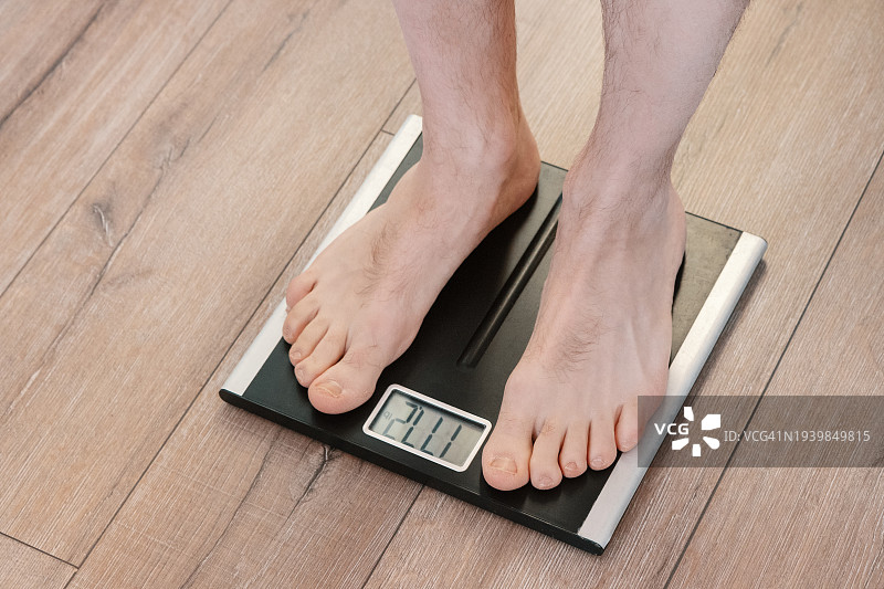 体重检查：男人赤脚站在体重秤上图片素材