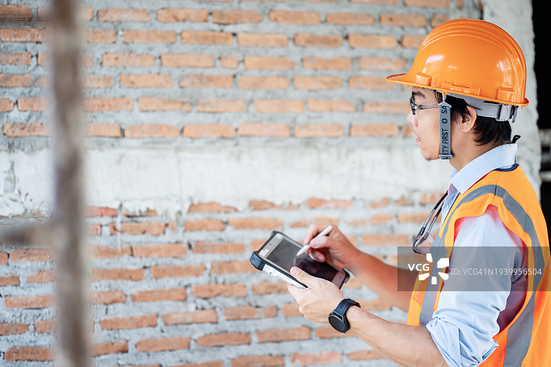 建筑项目中的准确预算和预测：日本男性项目经理使用平板电脑检查和评估数据图片素材