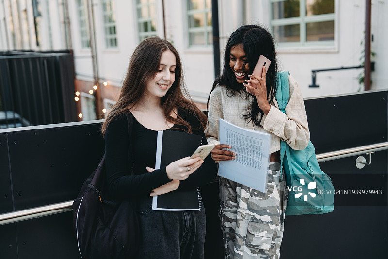 两位朋友站在街上，看着智能手机图片素材