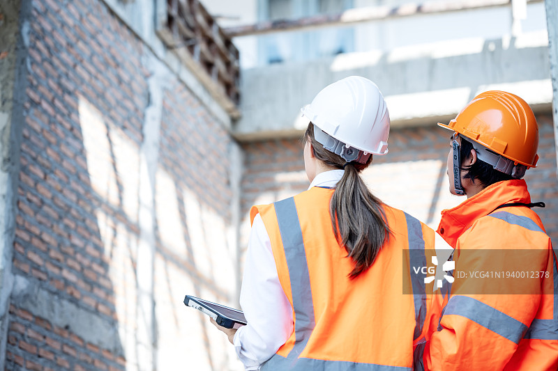 使用建筑管理解决方案交付高质量工作，提高项目效率。建筑团队在住宅开发工地上讨论进度和预算控制的后视图。图片素材