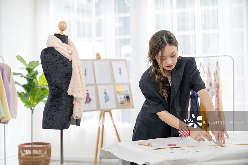 女设计师在工作室设计服装，体现小企业主的理念图片素材