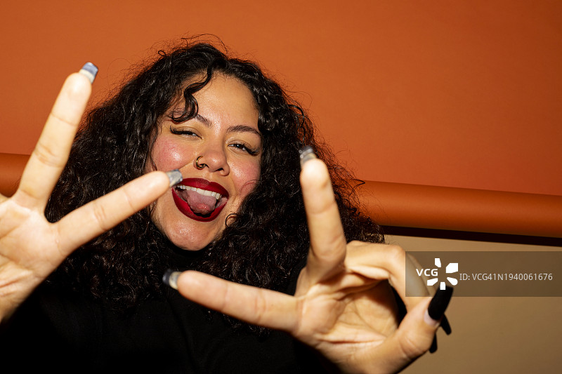 年轻女子吐舌头并比出和平手势图片素材