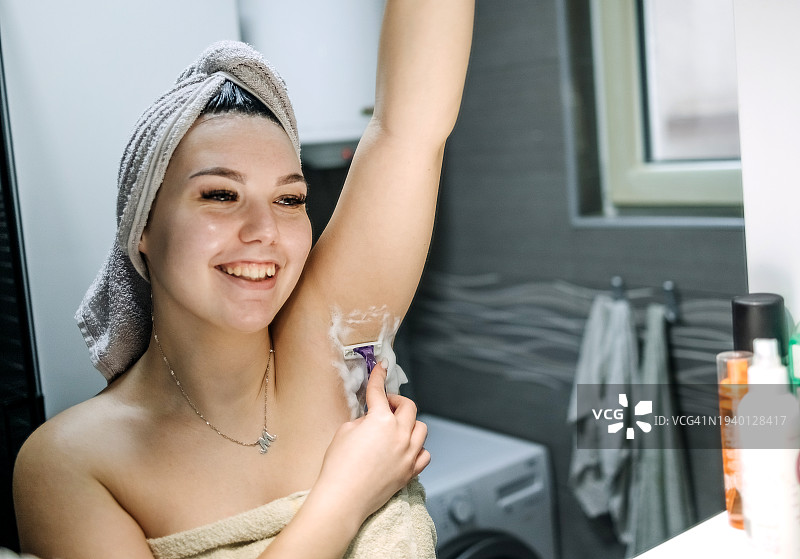 年轻女人个人护理，用剃须刀去除腋下毛发图片素材