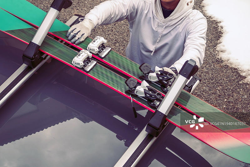 冬季，男人在车顶上安装滑雪板图片素材