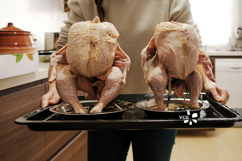 穿围裙的女人将整只生鸡放入烤箱图片素材