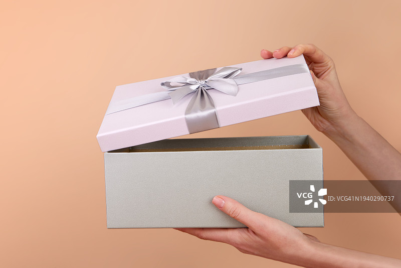 女人在米色背景下拿着礼品盒的局部照图片素材