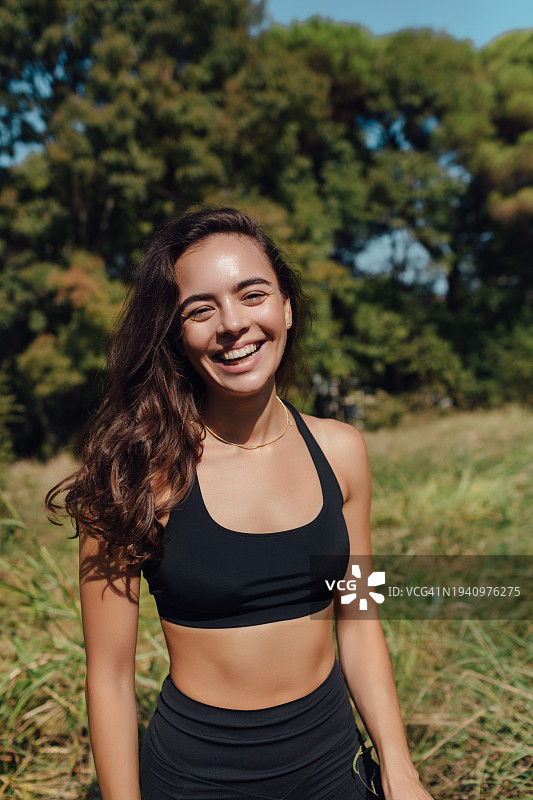 站在公园里看着镜头微笑的漂亮年轻欧洲女人图片素材