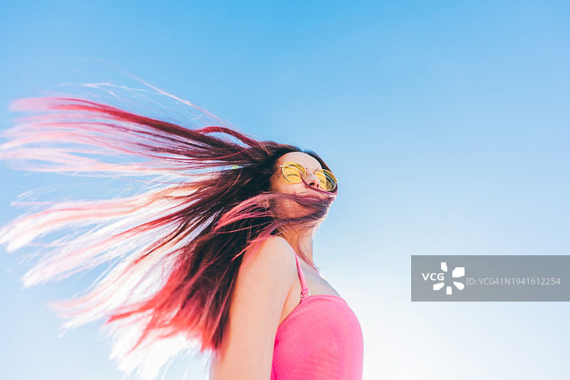 长长的粉色头发在空中飞舞的年轻女子肖像图片素材