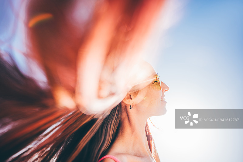 长长的粉色头发在空中飞舞的年轻女子肖像图片素材