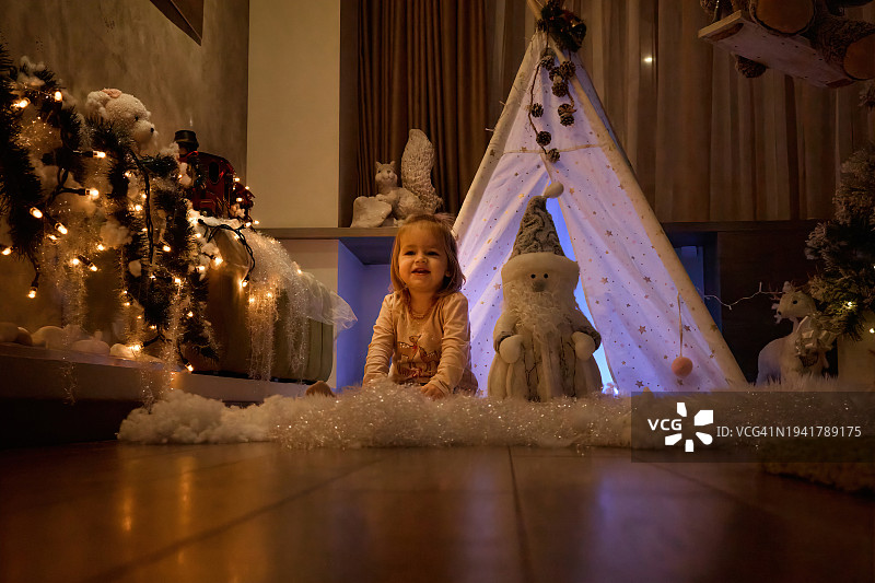 新年夜，小女孩坐在家里的游戏帐篷前图片素材