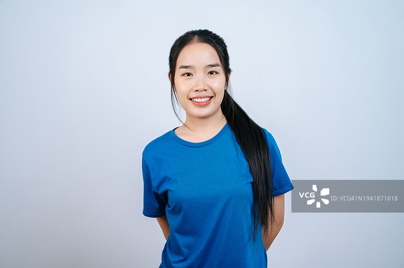 年轻的亚洲女子，梳着长马尾，对着镜头微笑，背景为白色图片素材