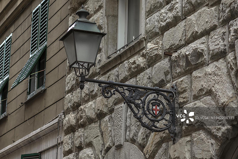意大利热那亚带有城市盾徽的房屋墙上的老式街灯图片素材