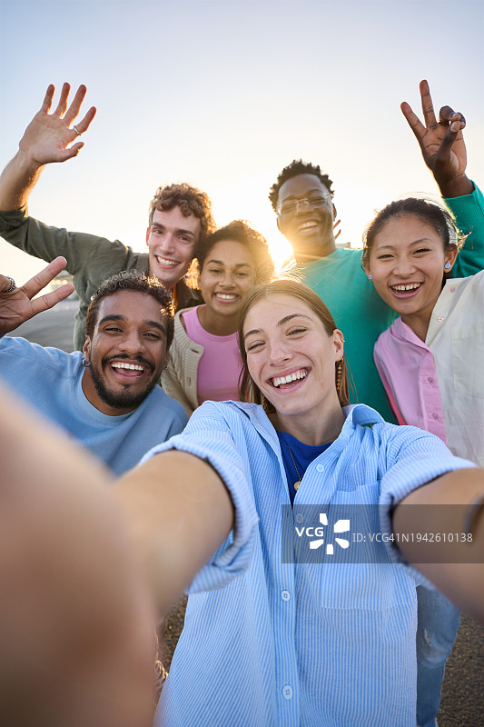 一群朋友用手机自拍，在户外玩耍，看着镜头图片素材