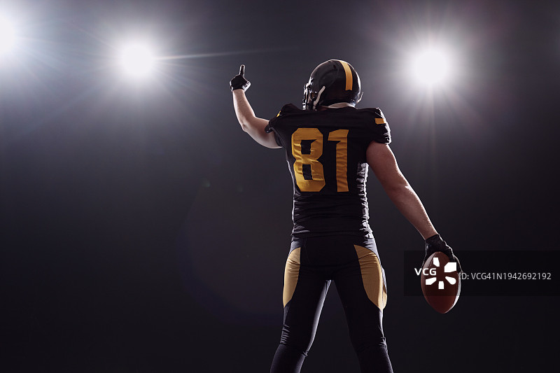 足球运动员庆祝进球，举手指向体育场灯光图片素材