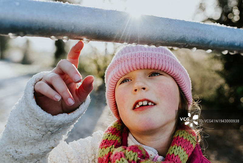 孩子被金属门上的小冰柱迷住了图片素材