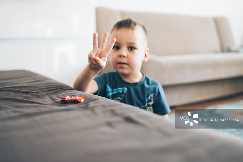 在家玩耍时伸出三根手指的男孩图片素材