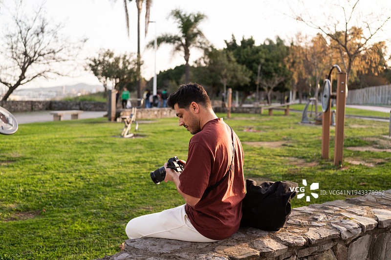 男人坐在公园里拿着照相机图片素材