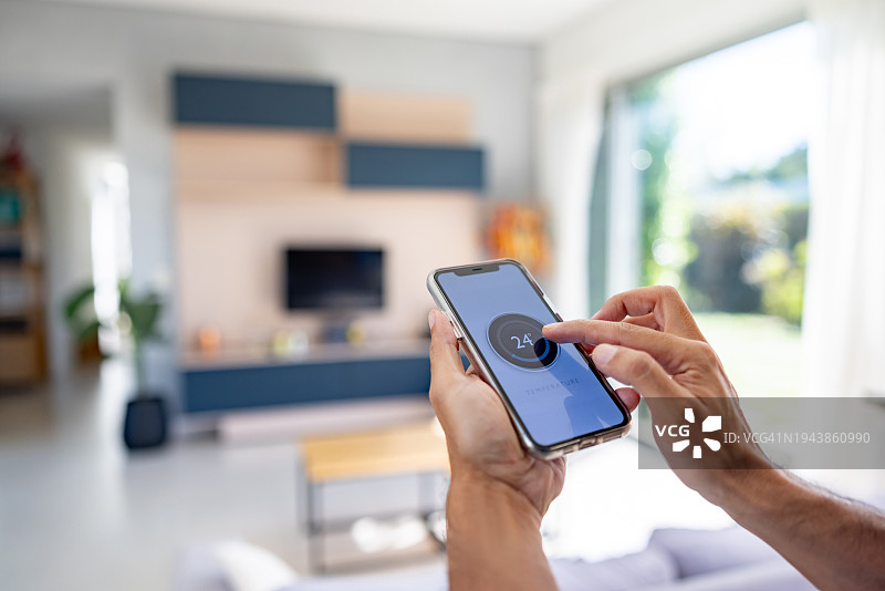 男子使用智能手机App控制房屋温度图片素材