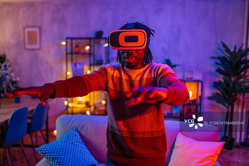 年轻男人晚上在家戴着VR头显玩游戏图片素材