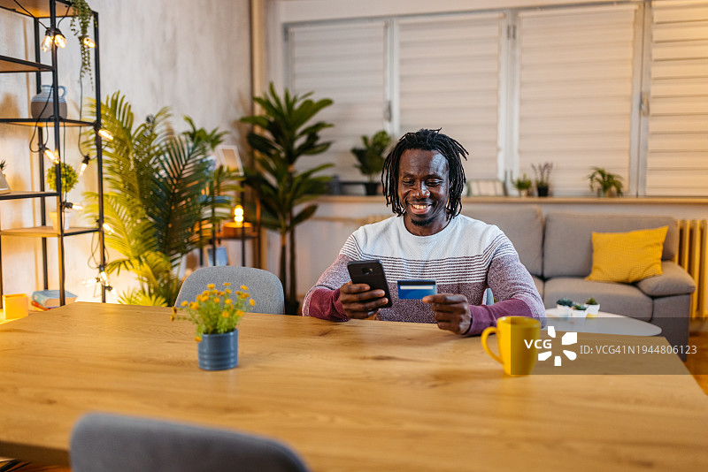 年轻男人晚上在家用智能手机在线购物图片素材
