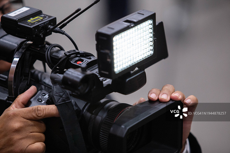 摄影师操作带LED灯摄像机图片素材