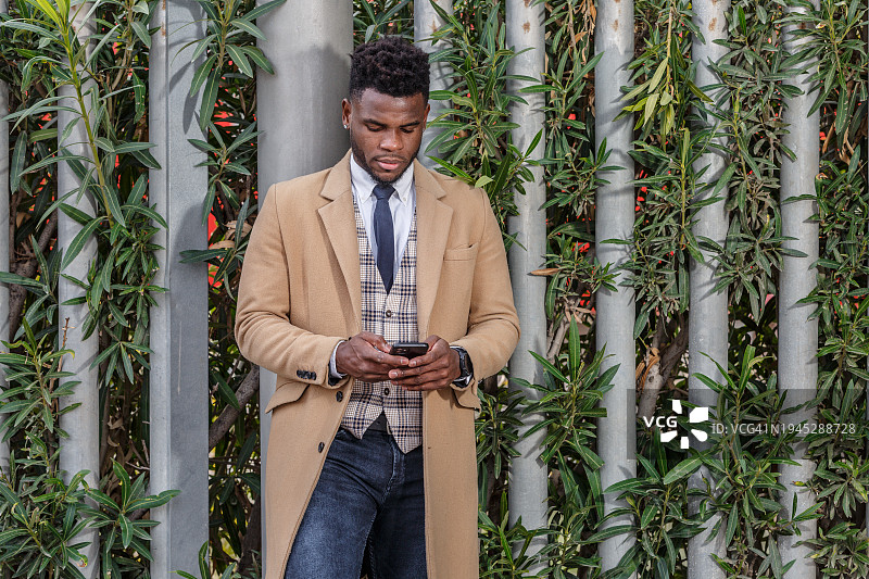 拿着智能手机站在栅栏旁的黑人图片素材