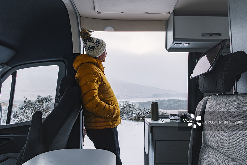 中年男人在苏格兰高地从房车里欣赏冬季雪景图片素材