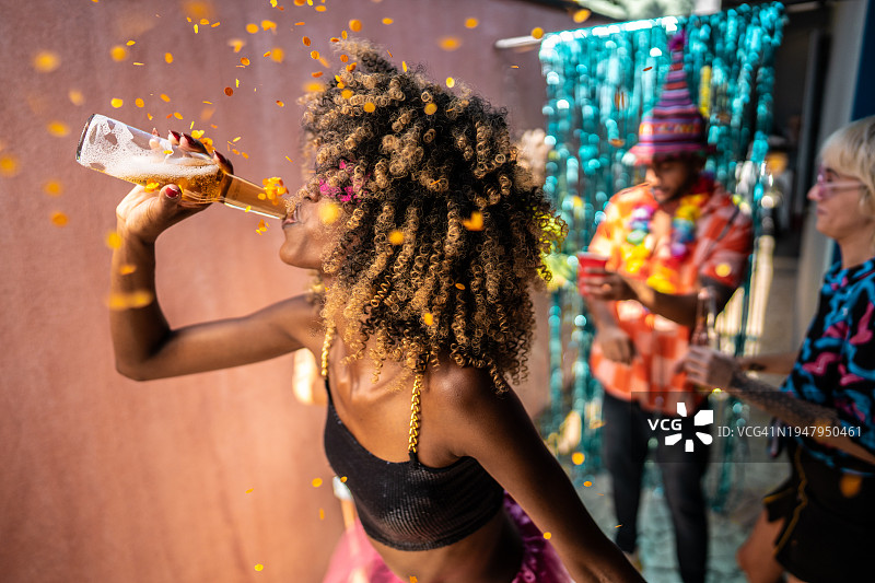 在家狂欢节期间喝啤酒跳舞的年轻女人图片素材