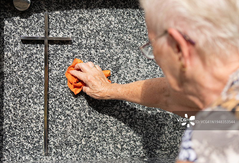 老妇人在墓地里清扫坟墓图片素材