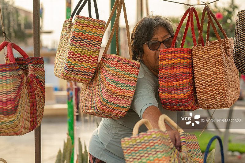 女人们看着待售的芦苇沙滩包图片素材