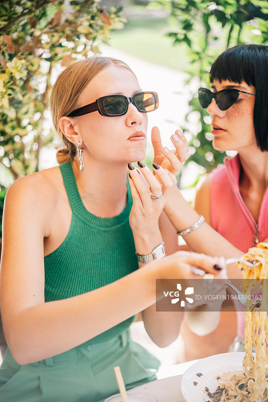 两个朋友戴着精美的眼镜和配饰，愉快地享用意大利面图片素材