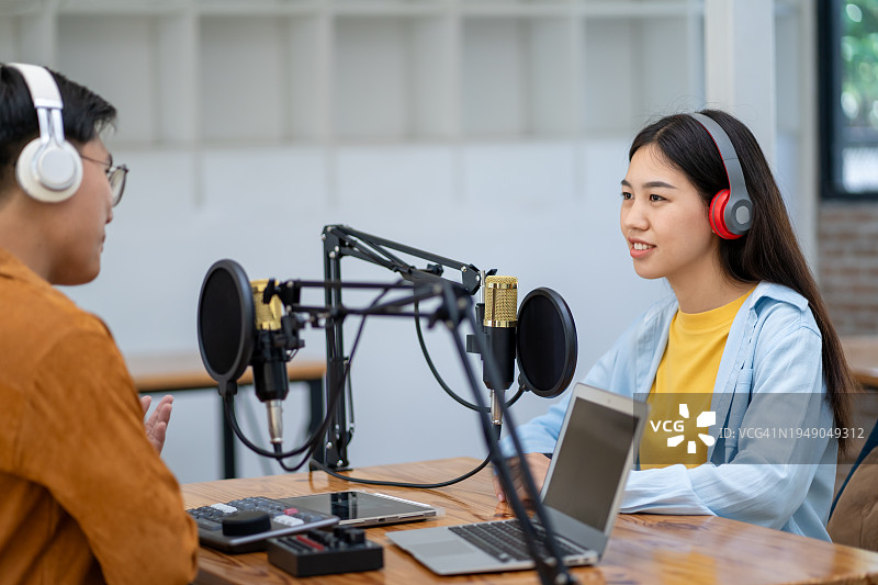 年轻男女在录音棚戴着耳机录制播客图片素材