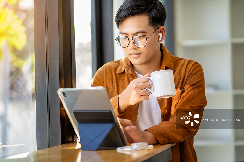 午休时间，年轻男人在办公室听播客的特写图片素材