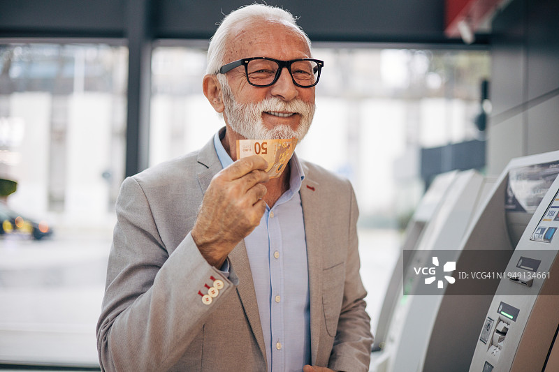 快乐的老年男人拿着欧元微笑图片素材