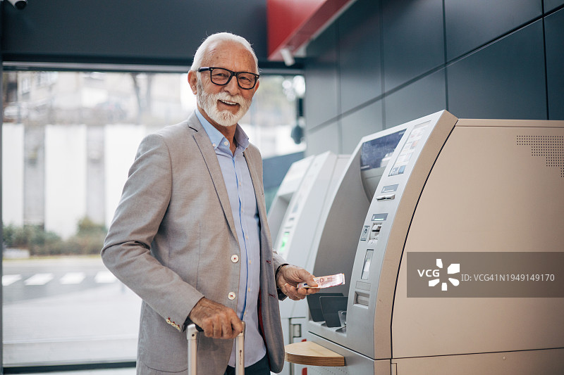 一位老人在火车站用借记卡从ATM取款图片素材