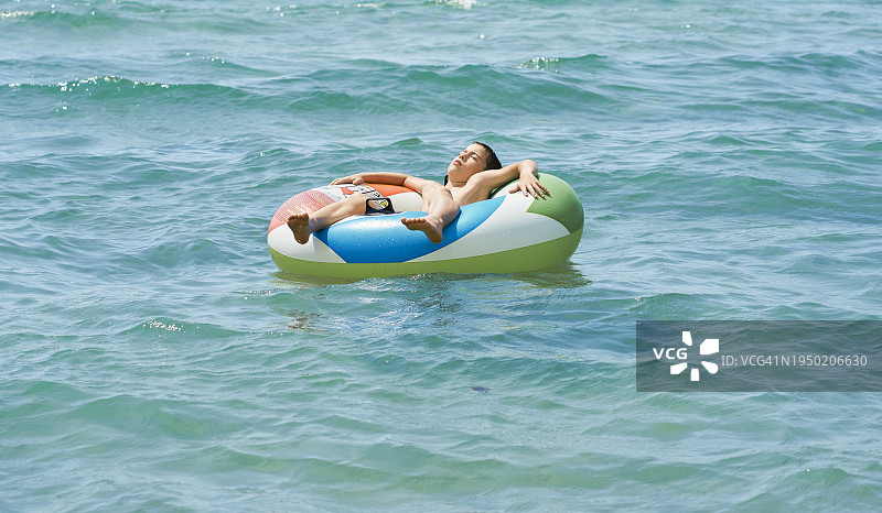 躺在海上充气轮胎上的小男孩图片素材