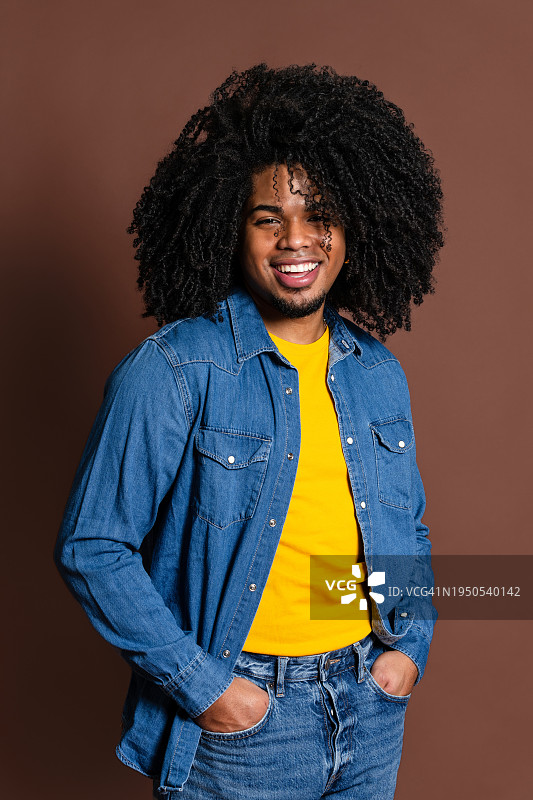 身穿牛仔夹克的快乐的非裔拉丁男人，面带灿烂笑容，影棚拍摄图片素材