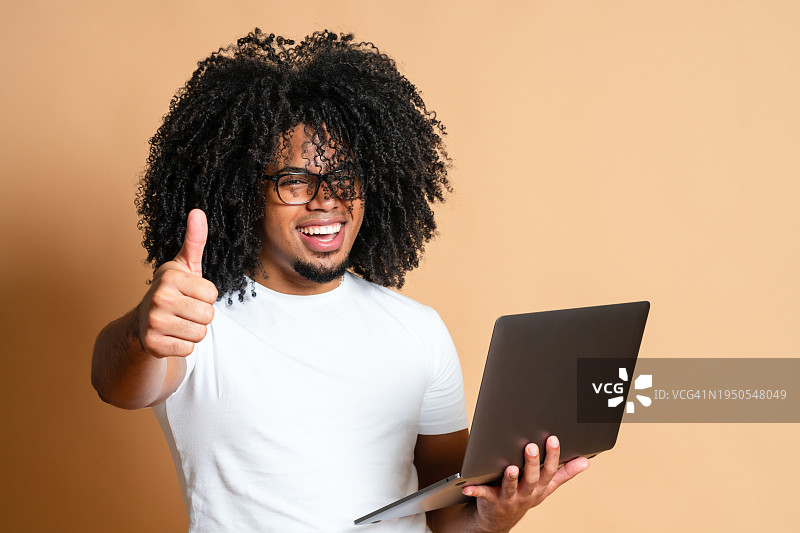 热情洋溢的蓬松爆炸头拉美裔男子在使用笔记本电脑图片素材